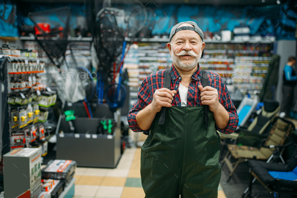 Fisherman tries on rubber jumpsuit in fishing shop - Stock Photo - Images