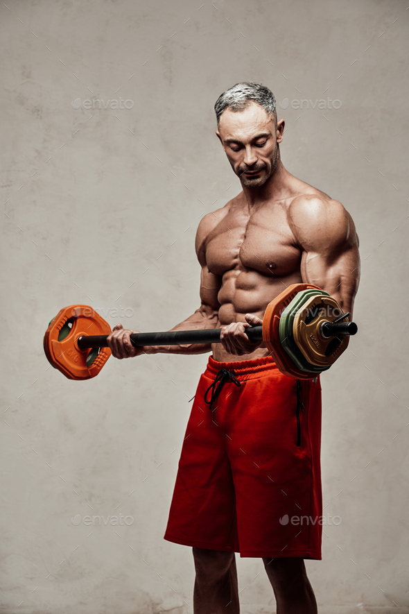 Handsome adult sportsman wearing sportswear posing for a camera while holding a barbell - Stock Photo - Images