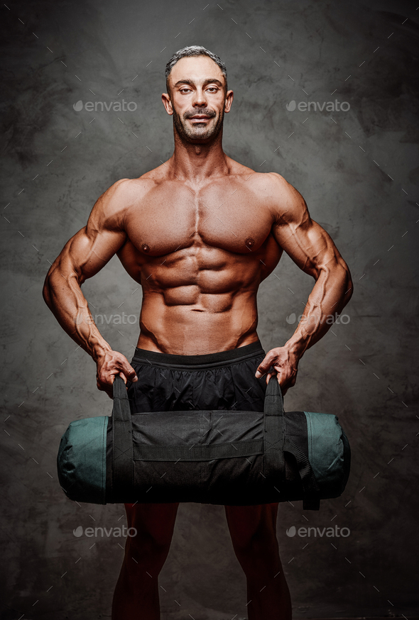 Athletic man isolated on a white background doing and exercise with a weight bag - Stock Photo - Images