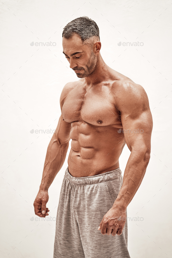 Fit man showcasing muscular arms. Studio portrait on white