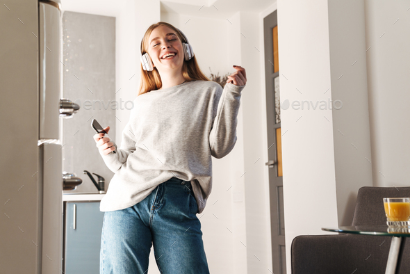 Girl holding mobile phone listening music with headphones - Stock Photo - Images