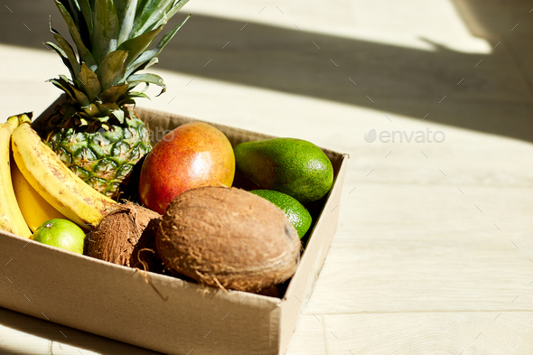Assortment of organic exotic fruits in box, sunlight.