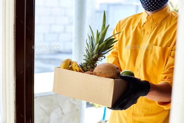 Courier man delivery box with exotic fruits food, contactless delivery.
