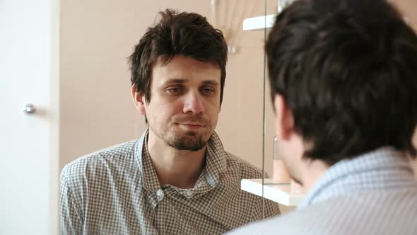 Tired Man Who Has Just Woken Up Looks at His Reflection in the Mirror and Sees His Scruffy