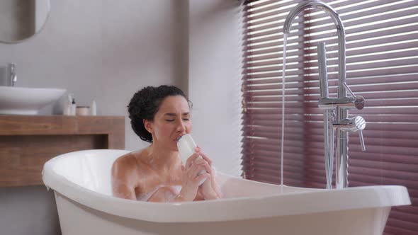 Funny Young Woman Sits in Foamy Bath Sings Using Shampoo Bottle As Microphone Enjoying Energetic alt