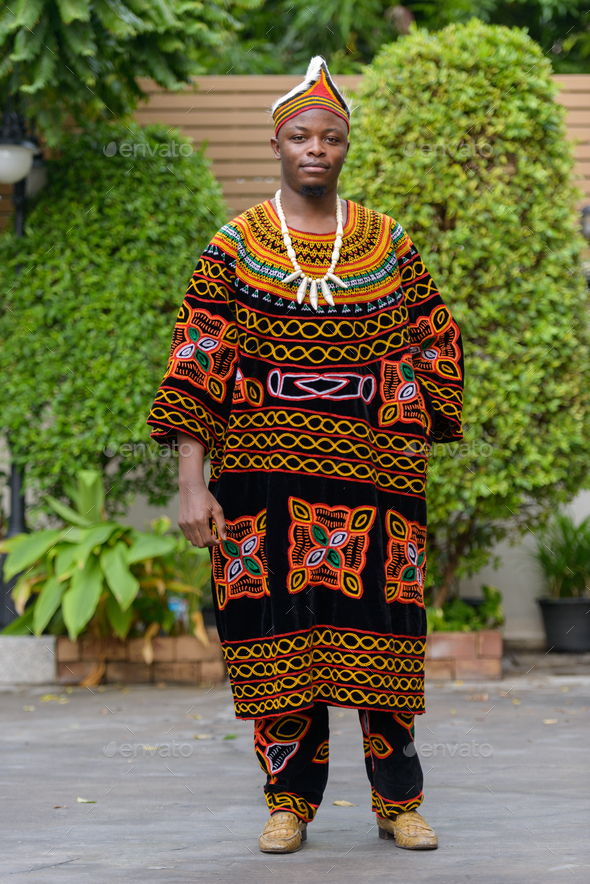 Full body shot of young African man wearing traditional clothing outdoors - Stock Photo - Images