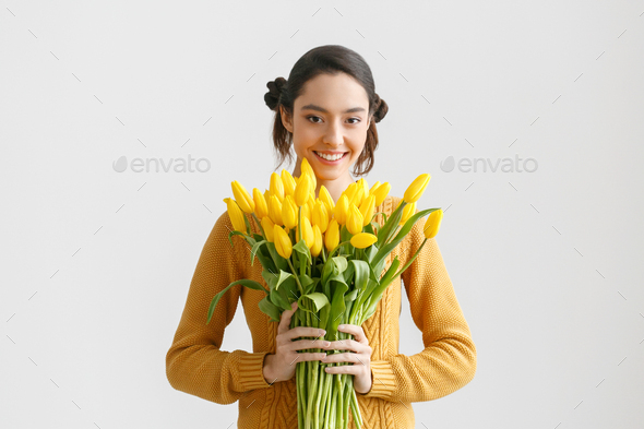 Woman with tulips. Young brunette girl with yellow flowers tulip - Stock Photo - Images