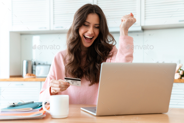 Emotional beautiful young woman holding credit card - Stock Photo - Images