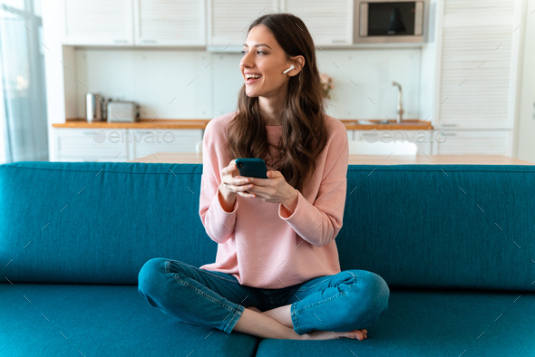 Woman sit indoors at home using mobile phone on sofa. - Stock Photo - Images