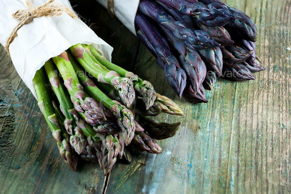 Fresh natural organic two bundles of green and purple asparagus vegetables on a wooden background - Stock Photo - Images
