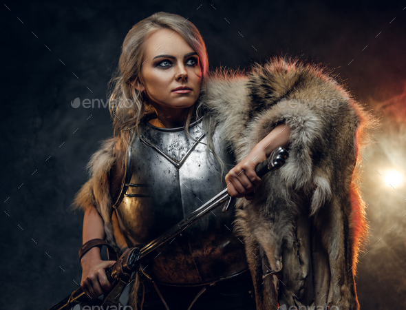 Portrait of a beautiful warrior woman holding a sword wearing steel cuirass and fur - Stock Photo - Images