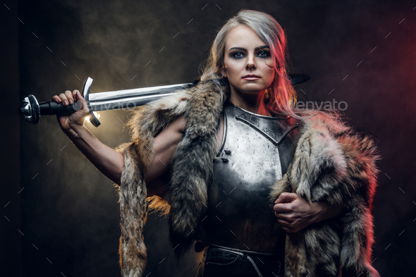 Portrait of a beautiful warrior woman holding a sword wearing steel cuirass and fur
