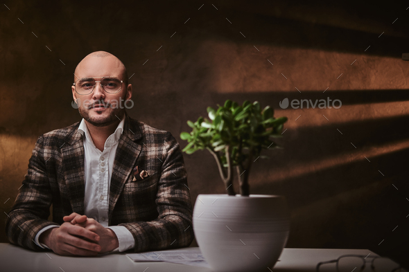 Bald serious thinking european well-dressed businessman sitting in the office - Stock Photo - Images