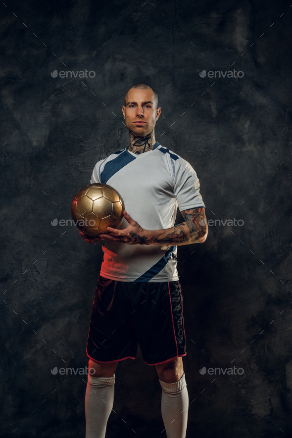 Bold and handsome soccer player holding a golden soccer ball - Stock Photo - Images