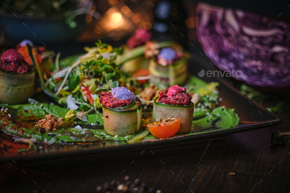 Haute cuisine vegetarian plate of appetizer rolls and a bowl of herbs served on a wooden table - Stock Photo - Images