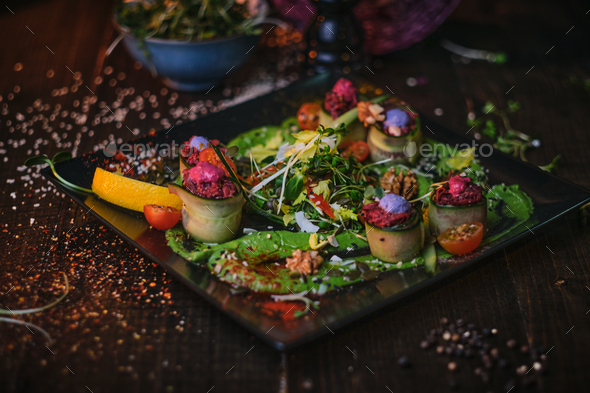 Haute cuisine vegetarian plate of appetizer rolls and a bowl of herbs served on a wooden table - Stock Photo - Images