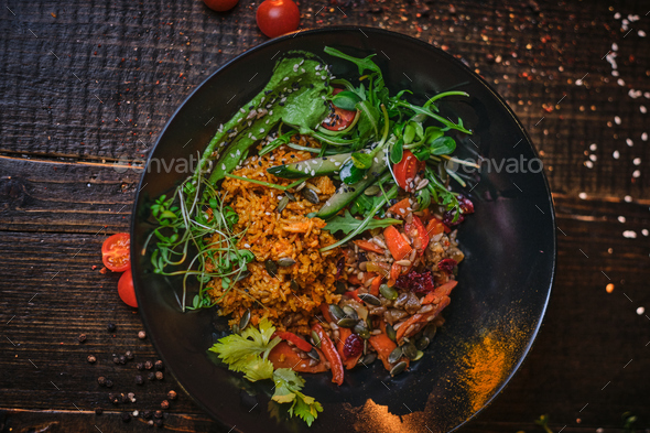 Cooked vegetarian bowl of plov on a wooden table - Stock Photo - Images