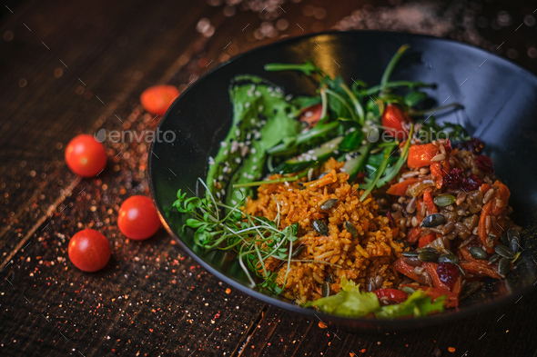 Cooked vegetarian bowl of plov on a wooden table - Stock Photo - Images