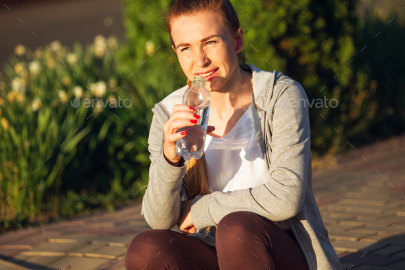 Young female runner, athlete resting after jogging in the city street in sunshine. Beautiful - Stock Photo - Images