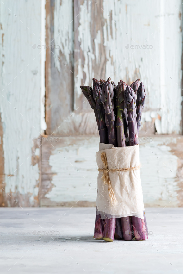 Raw organic purple asparagus spears ready for cooking healthy diet food on a light stone background - Stock Photo - Images