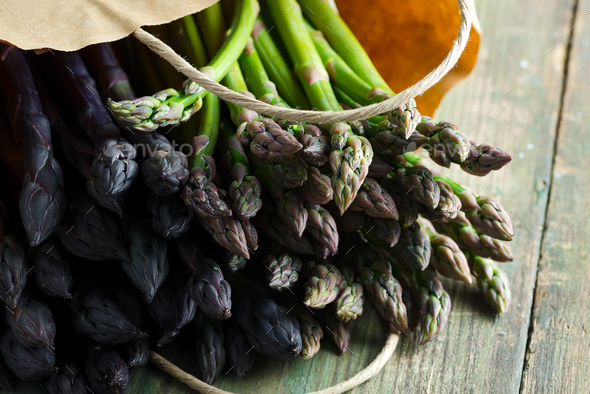 Paper bag with freshly picked raw organic natural purple asparagus spears on a wooden background - Stock Photo - Images
