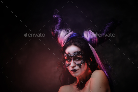 Cosplayer girl wearing dark demonic make up and horns posing in a studio on a dark background - Stock Photo - Images