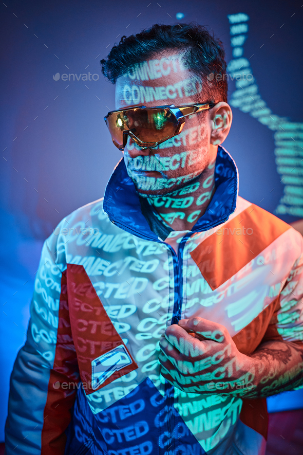 Inked attractive male posing in a neon vivid lights of a studio with text, looking cool - Stock Photo - Images