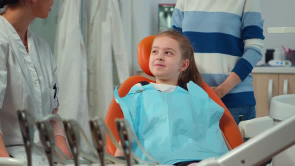Close Up of Kid Patient with Toothache Wearing Dental Bib Talking with Dentist alt