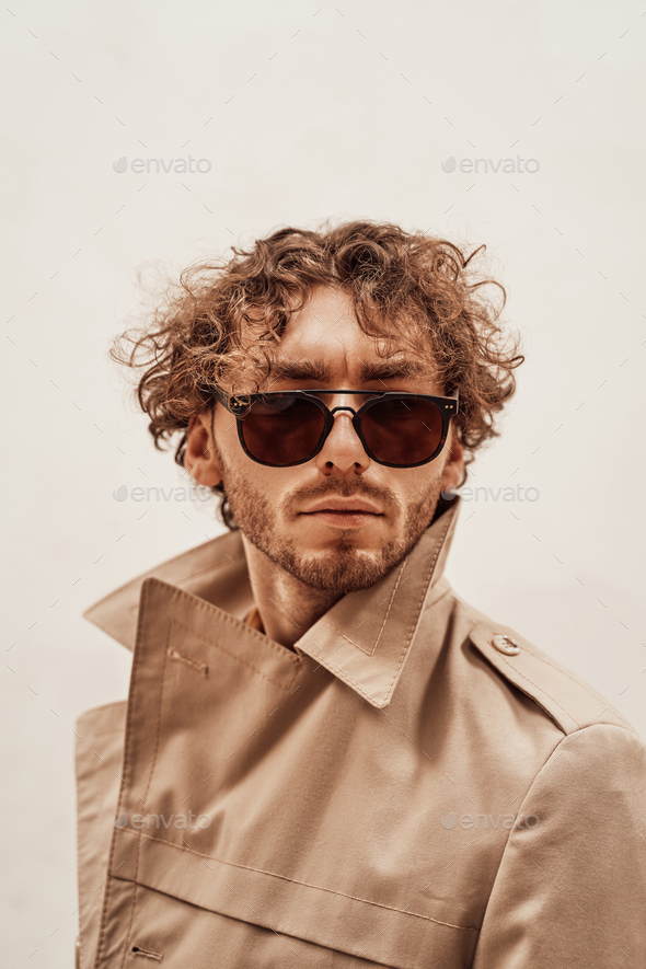 Portrait of a handsome casual guy with curly hair posing in the bright studio