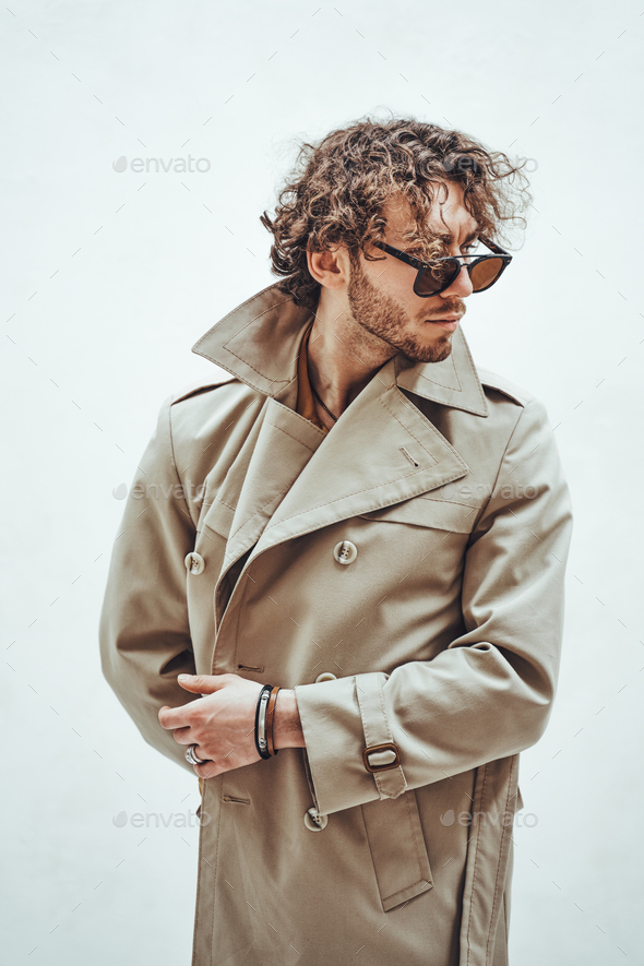 Portrait of a handsome casual guy with curly hair posing in the bright studio - Stock Photo - Images
