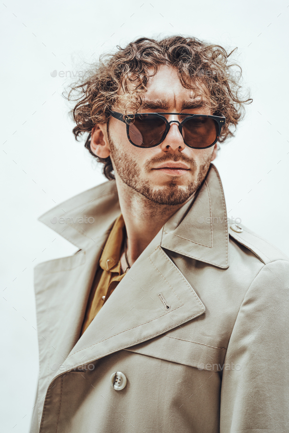 Portrait of a handsome casual guy with curly hair posing in the bright studio - Stock Photo - Images