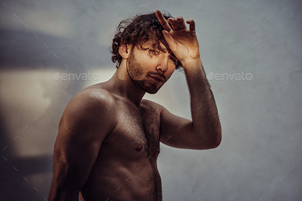 Young caucasian male model is naked and isolated on the grey background