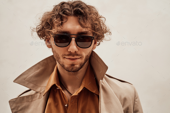 Portrait of a handsome casual guy with curly hair posing in the bright studio - Stock Photo - Images
