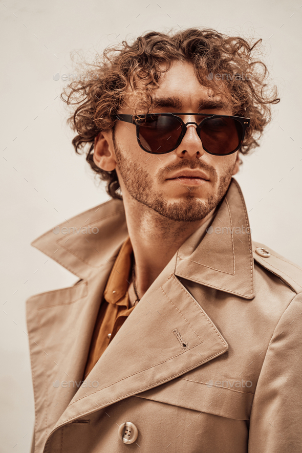 Portrait of a handsome casual guy with curly hair posing in the bright studio - Stock Photo - Images