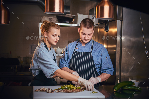 Male chef with assistant standing in a kitchen, preparing food in a luxury restaurant - Stock Photo - Images