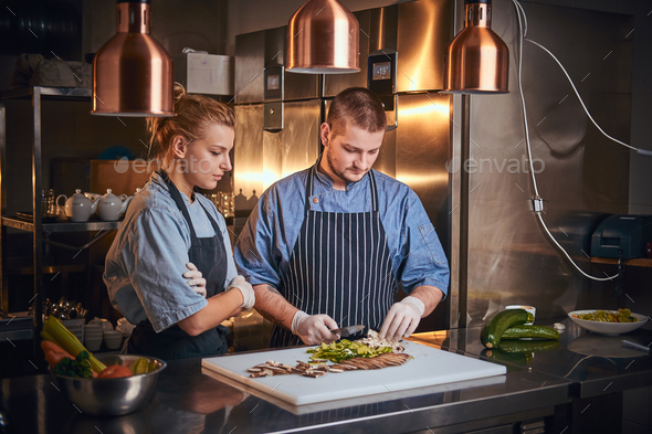 Male chef with assistant standing in a kitchen, preparing food in a luxury restaurant - Stock Photo - Images
