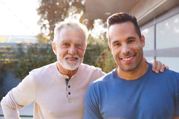 Portrait Of Loving Senior Hispanic Father With Adult Son In Garden At ...