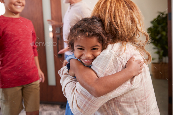 Grandparents Greeting Grandchildren At Front Door As They Comes To Visit