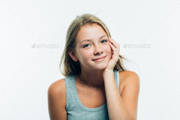 Beautiful young woman is touching her chin. Portrait of girl with freckles  and long blonde hair. Stock Photo by kiraliffe