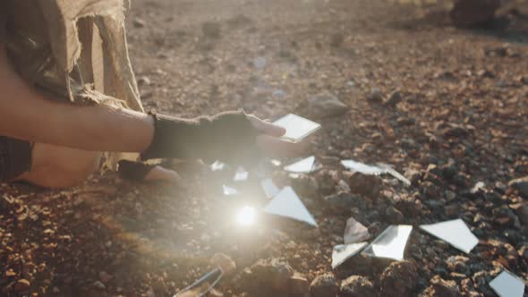 Woman Looking at Pieces of Broken Mirror in Dystopian World alt
