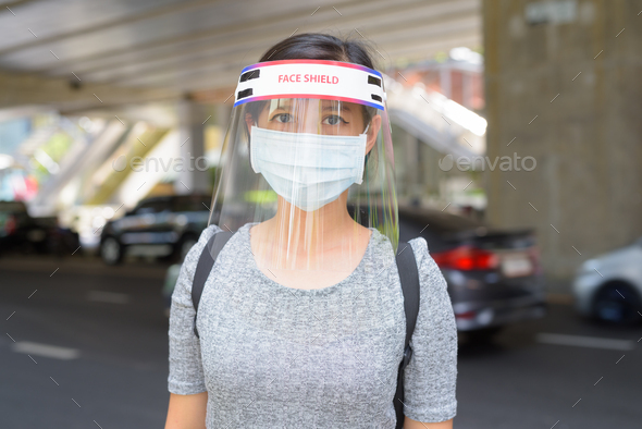 Young Asian woman wearing mask and face shield for protection from corona virus outbreak in the city