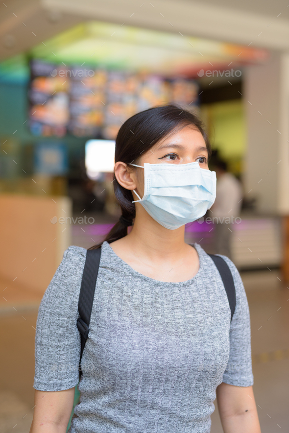 Young Asian woman with mask for protection from corona virus outbreak inside the restaurant