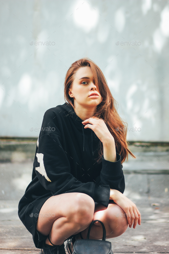 A young model girl in a pink hoodie, blue jeans and sneakers jumping and  posing in the interior. A young woman in casual sports attire Stock Photo |  Adobe Stock