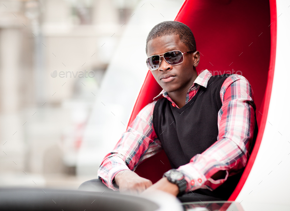 handsome young man wearing sunglasses sitting with bottles of red