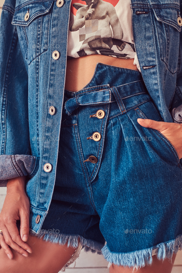 Cropped image of a sexy slim young girl wearing short denim shorts and jeans jacket.