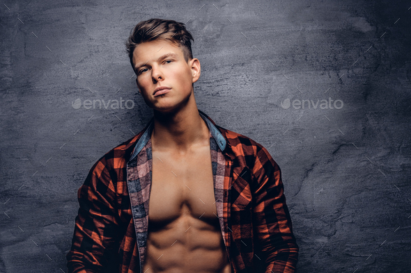 Sexy guy with unbuttoned fleece shirt posing at a studio.
