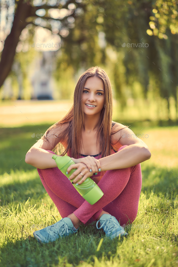 Premium Photo | Latin woman doing yoga poses grasping the foot in the park  on green grass with a pink outfit