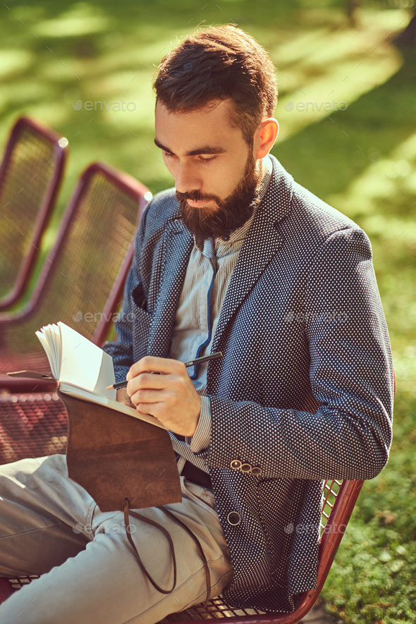 Bearded male with a stylish haircut in casual clothes in a park.