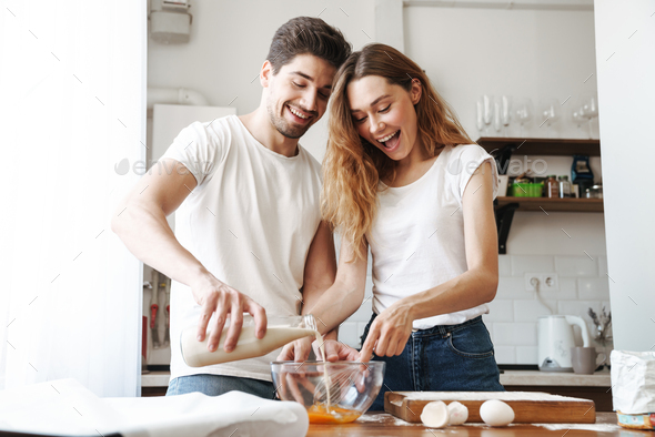 Image of positive young couple cooking breakfast together in apartment