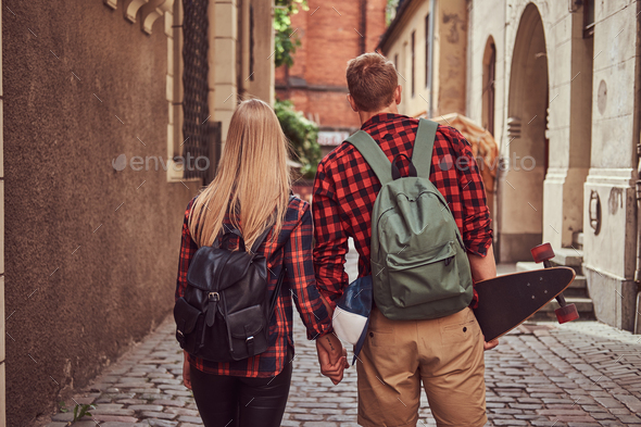 Handsome skater and his girlfriend walking around an old narrow streets of Europe. - Stock Photo - Images